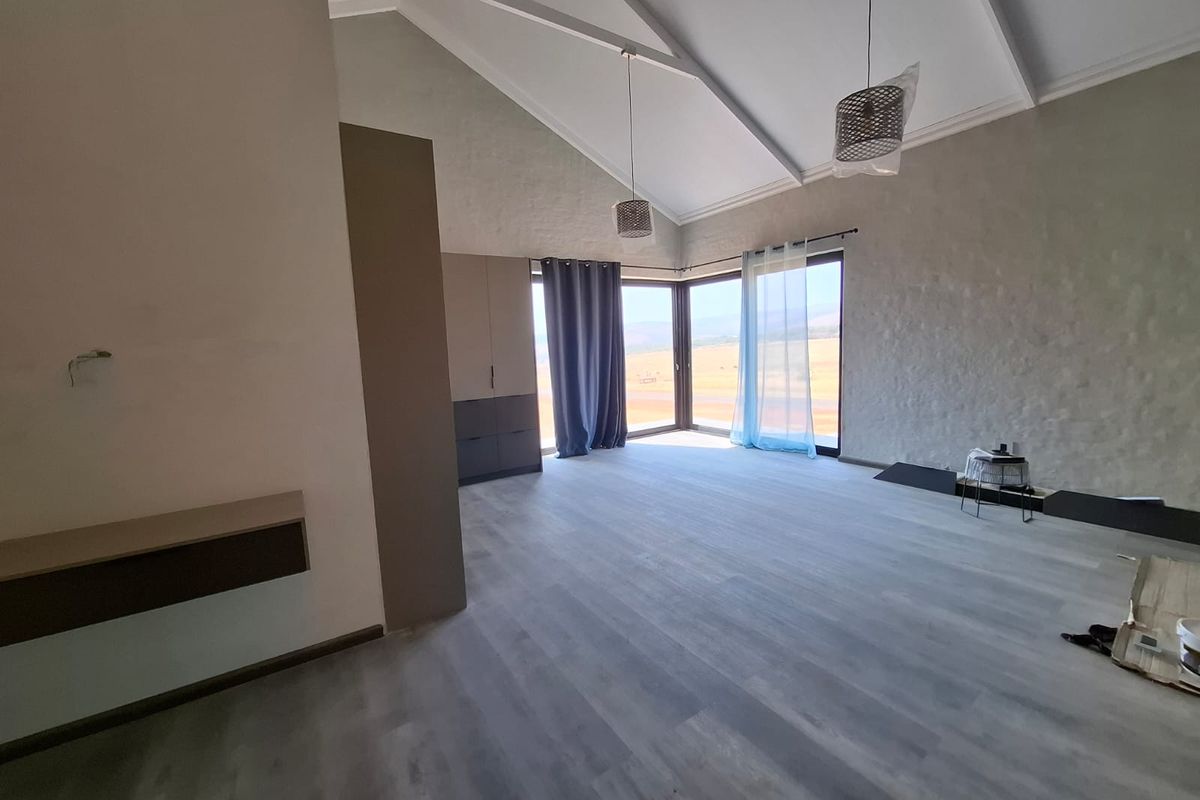 Spacious bedroom featuring high vaulted ceilings, modern laminate flooring, built-in cabinetry, and large corner windows offering expansive views.