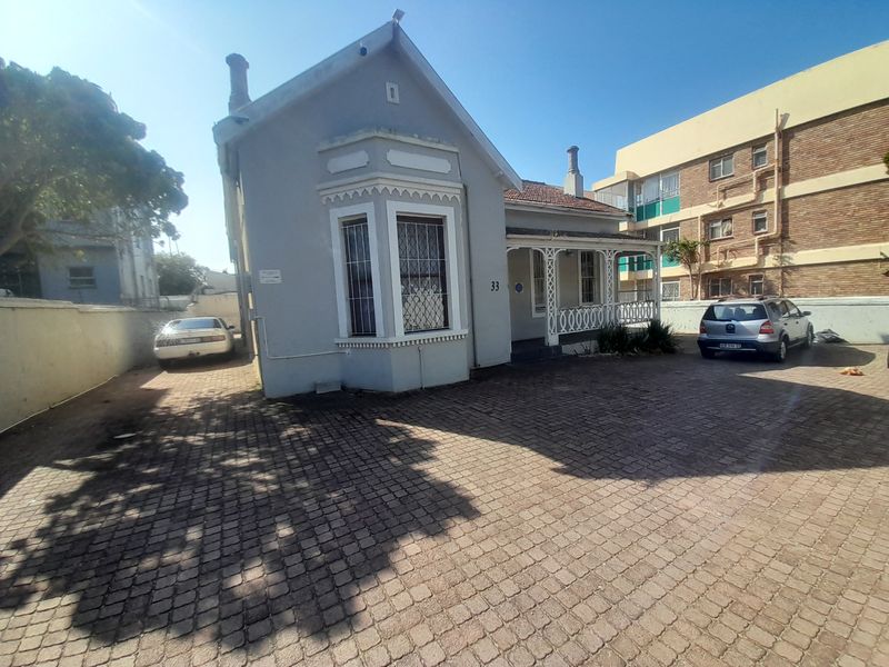 Front elevation of a character cottage featuring a bay window, covered veranda with decorative fretwork, and a paved driveway area.