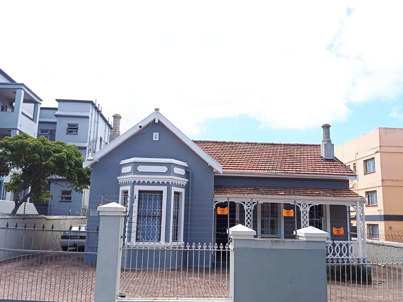 A charming single-story residence featuring a classic tiled roof, a bay window, and a covered veranda, secured by perimeter fencing and a paved driveway.