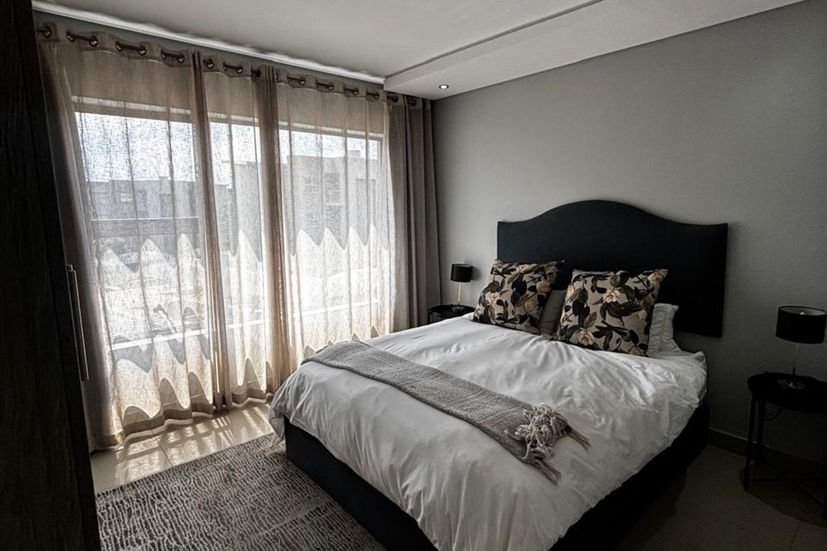 A well-maintained bedroom featuring tiled flooring, recessed downlighting, and a large sliding glass door providing access to an outdoor area.