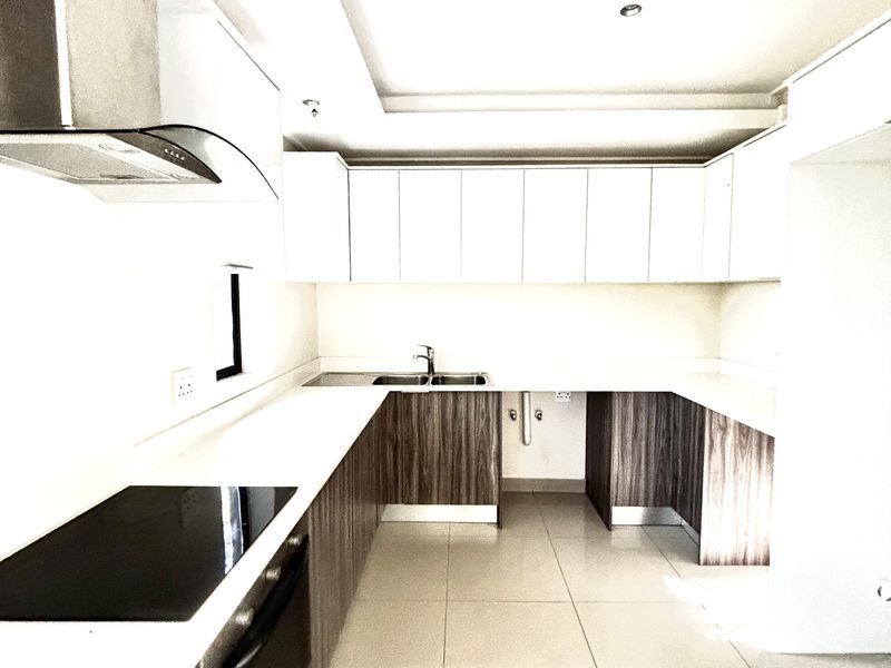 Modern kitchen featuring sleek two-tone cabinetry, integrated electric hob, stainless steel extractor fan, and tiled flooring in a clean, minimalist layout.