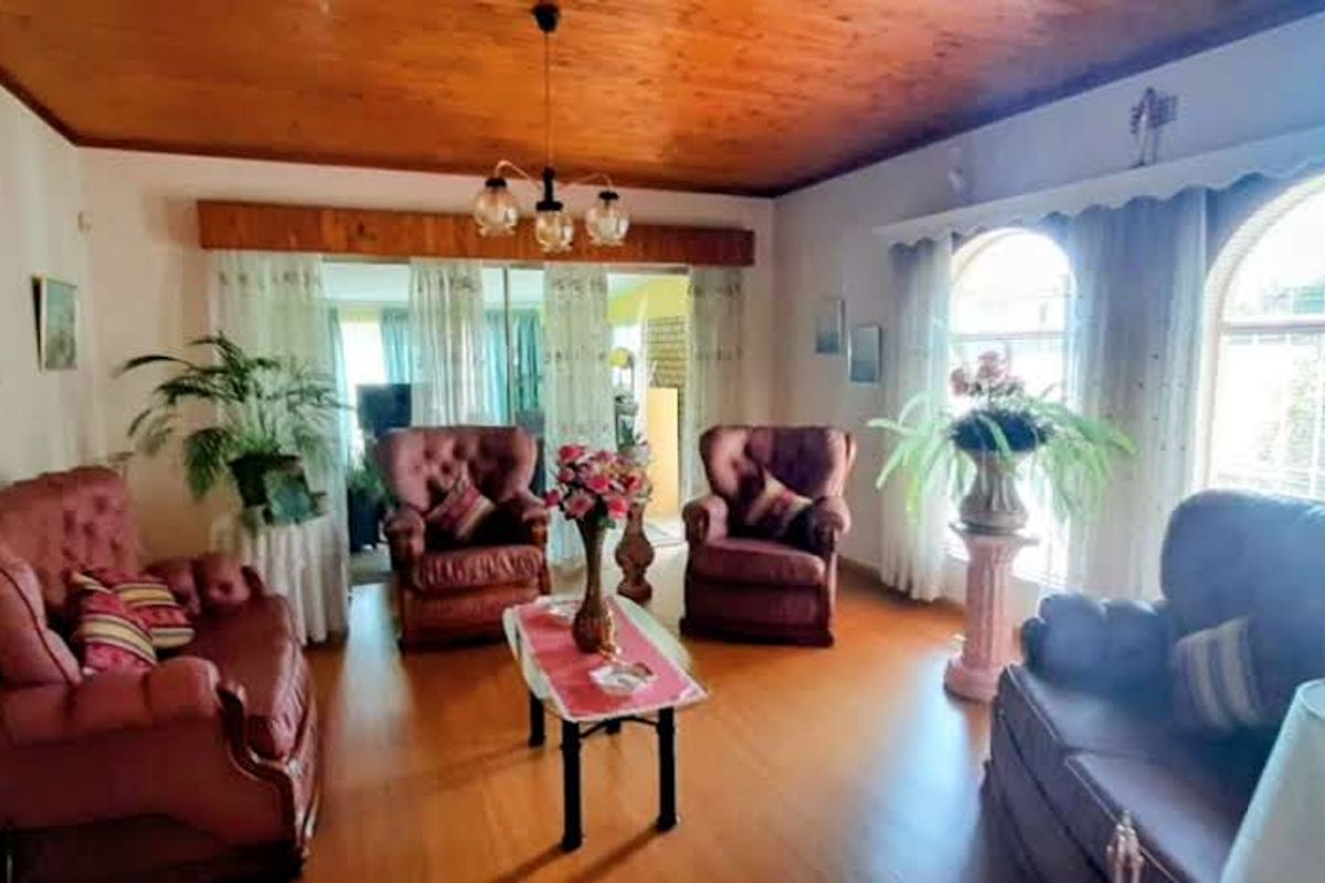 A spacious living room featuring warm wood-paneled ceilings, laminate flooring, and large arched windows that provide ample natural light.
