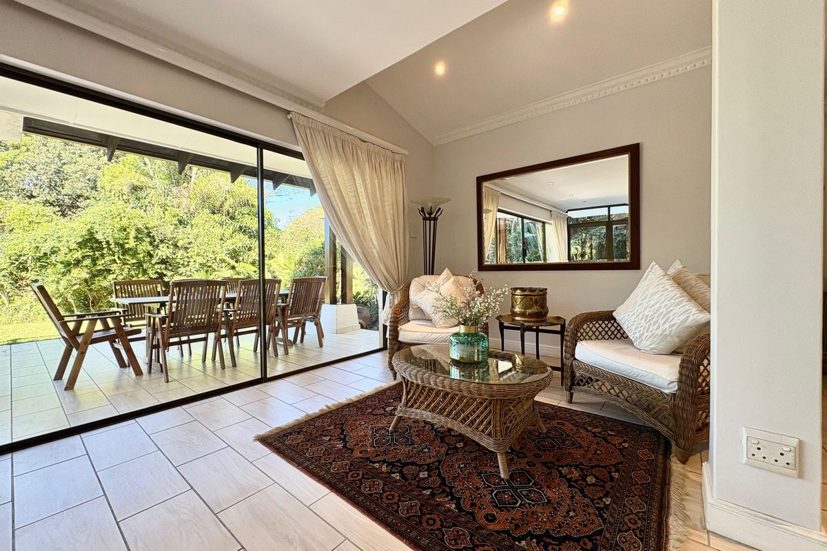 A bright living area featuring large sliding glass doors that open onto a covered patio, creating a seamless indoor-outdoor flow.