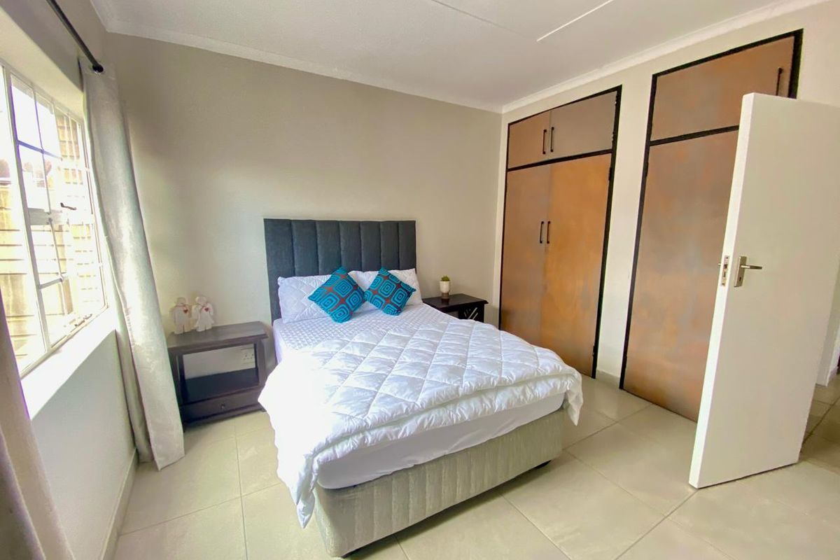 A bedroom featuring tiled flooring and built-in cupboards with a neutral color palette.