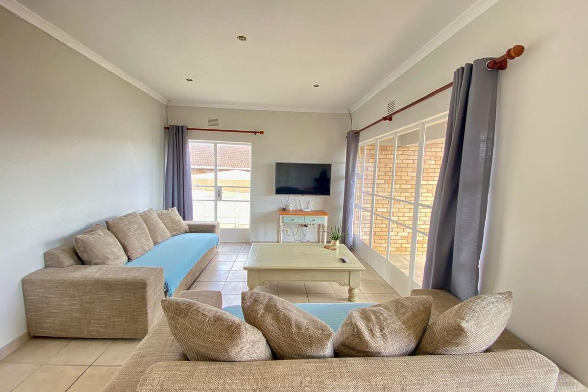 A bright living room featuring tiled flooring, recessed downlights, and large sliding glass doors providing access to the exterior.