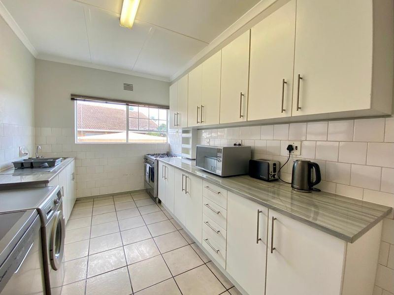 A functional kitchen featuring white cabinetry, laminate countertops, tiled backsplash, and a gas stove, offering a clean and practical workspace.