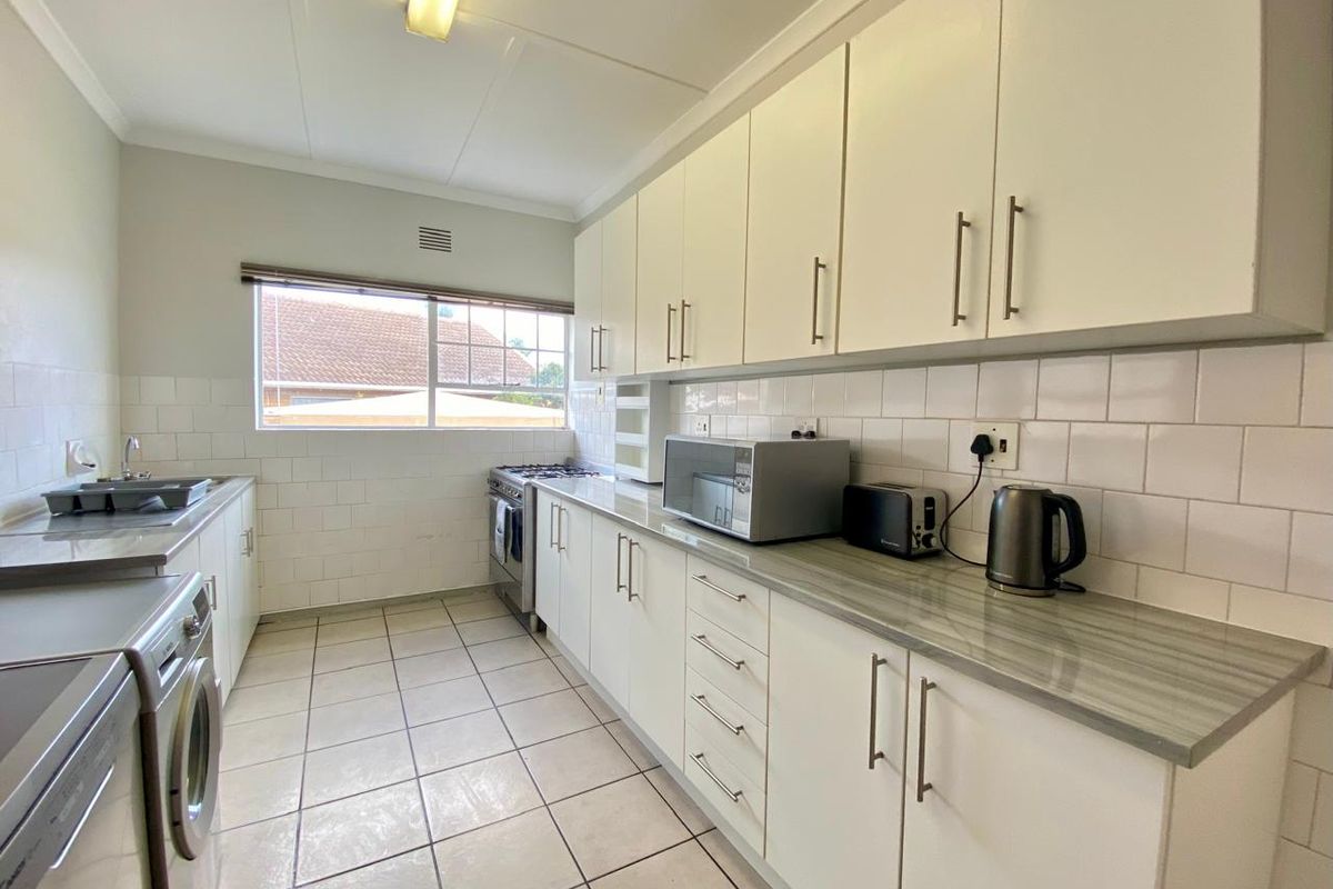 A functional kitchen featuring white cabinetry, laminate countertops, tiled backsplash, and a gas stove, offering a clean and practical workspace.