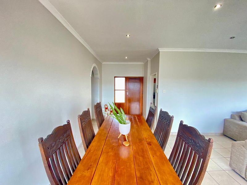A bright dining area featuring tiled flooring, recessed downlighting, and a decorative archway leading to an adjacent space.
