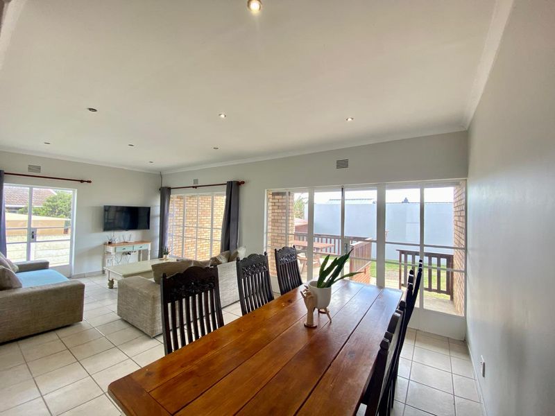 Spacious open-plan living and dining area featuring neutral tiled flooring, recessed lighting, and large glass doors providing ample natural light and outdoor access.