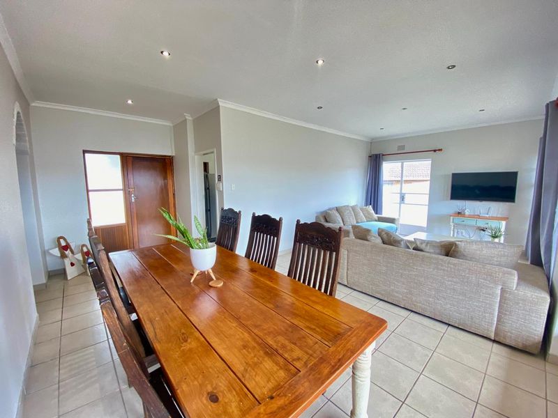 Open plan living and dining area featuring neutral walls, ceramic tiled flooring, recessed downlighting, and access to the exterior via a sliding glass door.