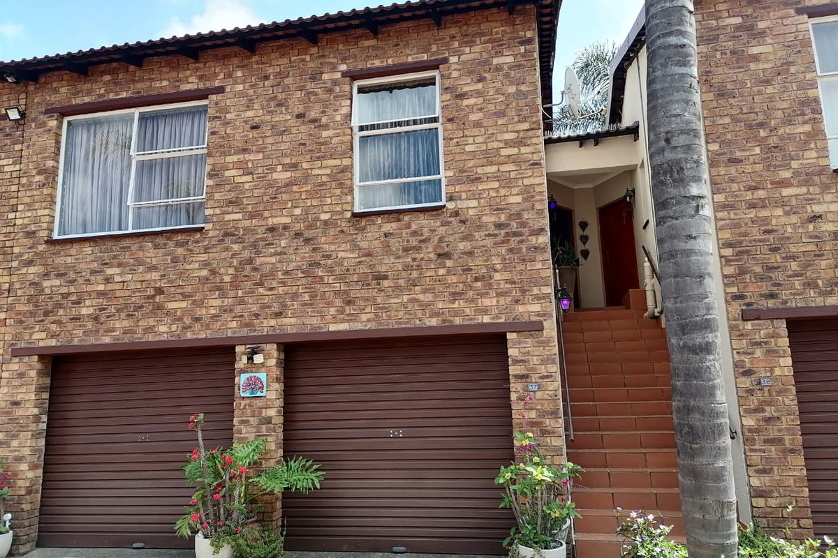Front elevation of a double-story townhouse featuring a face brick facade, double garage, and an external staircase leading to the entrance.