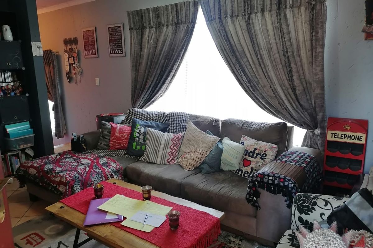 A comfortable living room area featuring tiled flooring and large windows with curtain treatments, providing a functional space for relaxation.