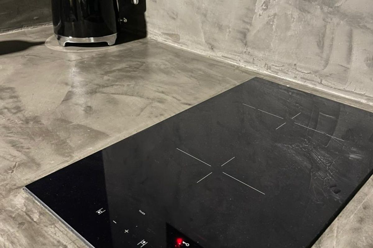 Modern kitchen area featuring a sleek induction cooktop set into a polished concrete countertop with a contemporary finish.
