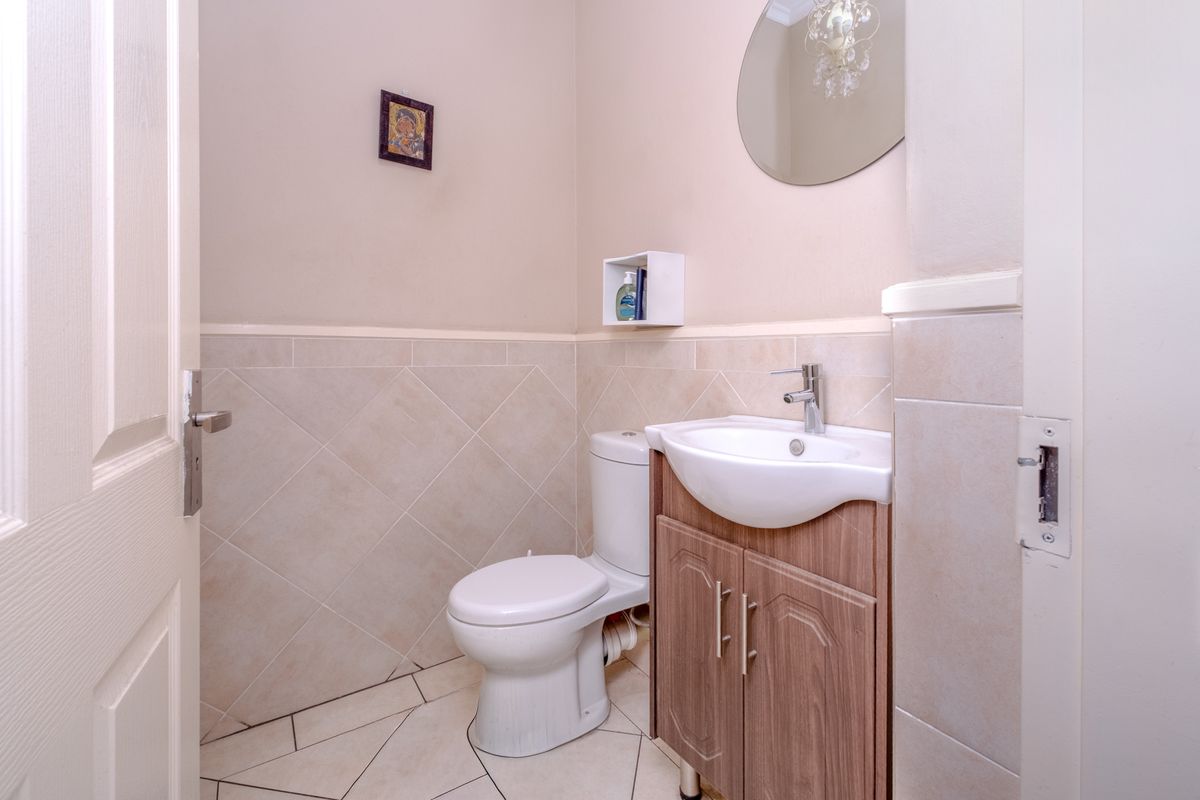 A compact guest bathroom featuring a vanity cabinet with a basin, a toilet, and neutral half-height wall tiling.