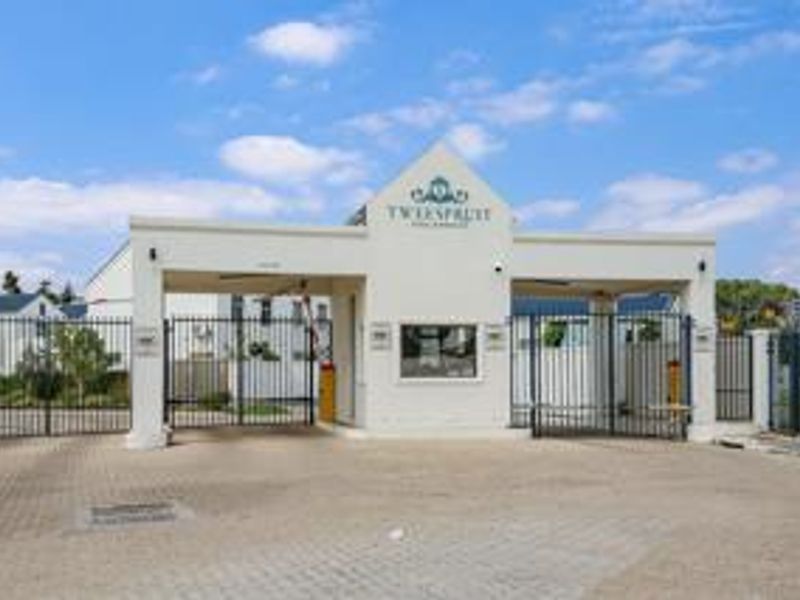 The main entrance and security gatehouse of the Tweespruit apartment complex, featuring paved access and secure perimeter fencing.
