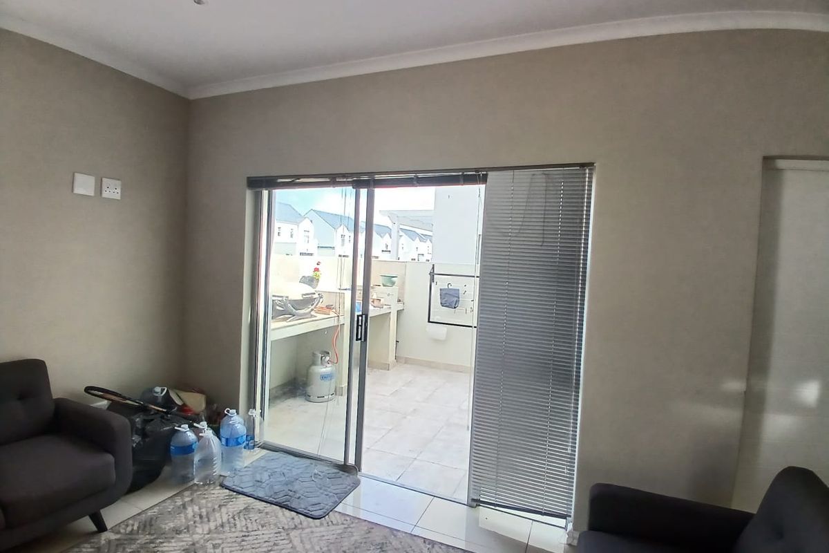 A living room featuring tiled flooring and a sliding glass door that provides direct access to an outdoor patio area.