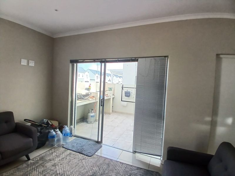 A living room featuring tiled flooring and a sliding glass door that provides direct access to an outdoor patio area.