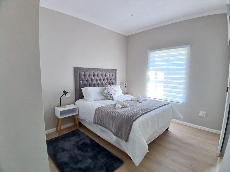 A well-maintained bedroom featuring neutral wall tones, light laminate flooring, and modern roller blinds, providing a clean and comfortable living space.