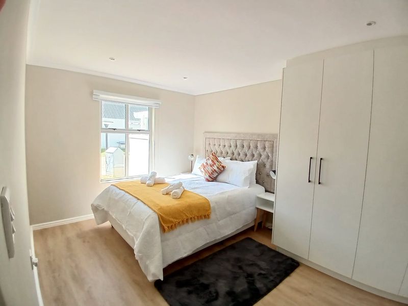 A well-maintained bedroom featuring neutral walls, laminate flooring, recessed lighting, and a spacious built-in wardrobe.