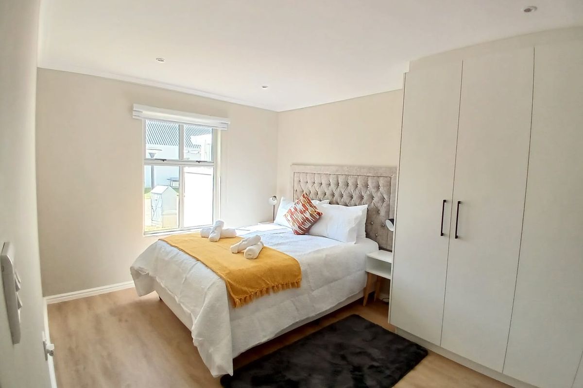 A well-maintained bedroom featuring neutral walls, laminate flooring, recessed lighting, and a spacious built-in wardrobe.