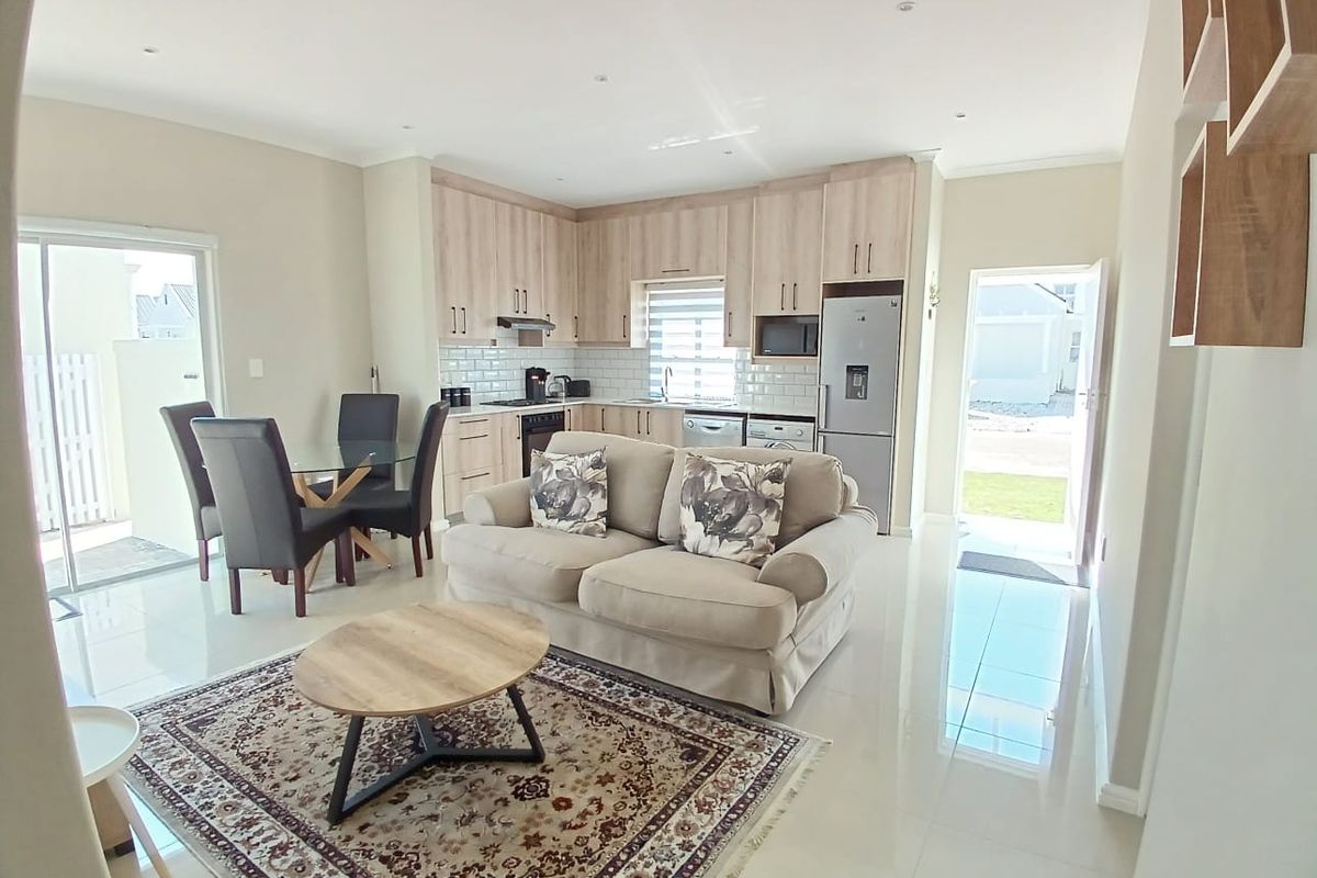Modern open-plan living area featuring a well-appointed kitchen with light wood cabinetry, subway tile backsplash, and direct access to the outdoor patio.