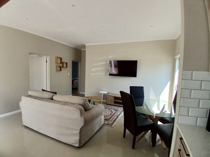 Open-plan living and dining area featuring neutral wall tones, recessed lighting, and tiled flooring, seamlessly connected to the kitchen space.
