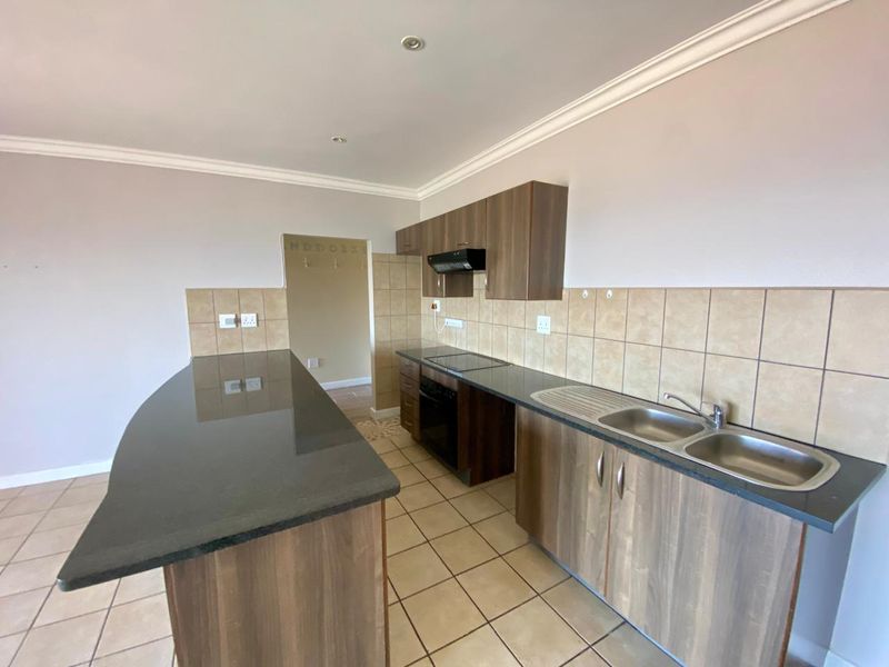 A functional kitchen featuring wood-finish cabinetry, granite countertops, a breakfast bar, and built-in appliances, including an oven and extractor fan.