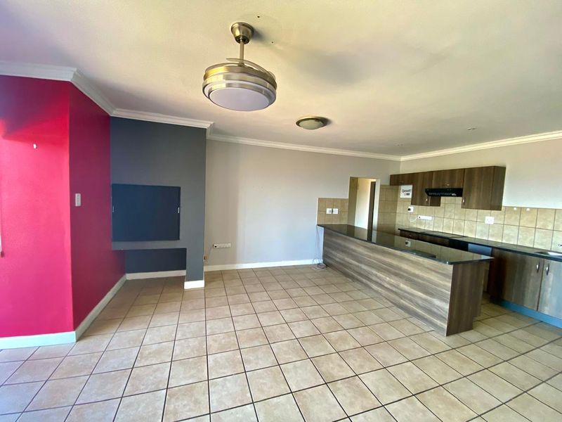 Spacious open-plan living and kitchen area featuring tiled flooring, built-in cabinetry with granite countertops, a ceiling fan, and a built-in fireplace.