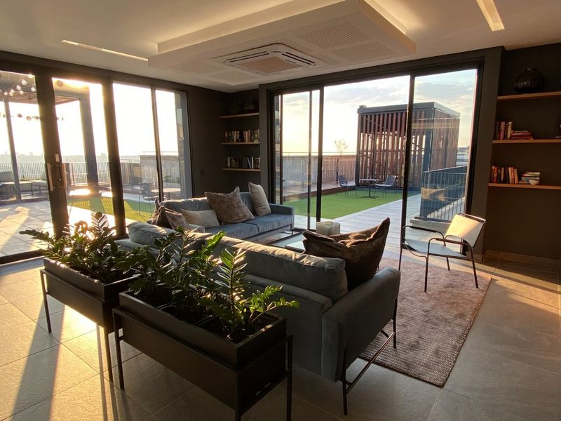 Modern open-plan living area featuring floor-to-ceiling sliding glass doors, recessed ceiling lighting, integrated air conditioning, and direct access to a spacious private balcony.