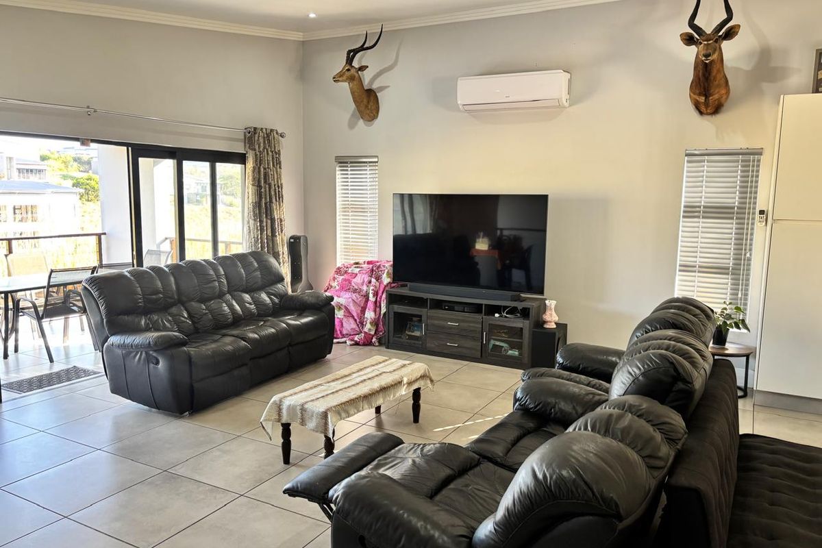 Spacious living room featuring large format floor tiles, sliding glass doors leading to a patio, and a wall-mounted air conditioning unit.