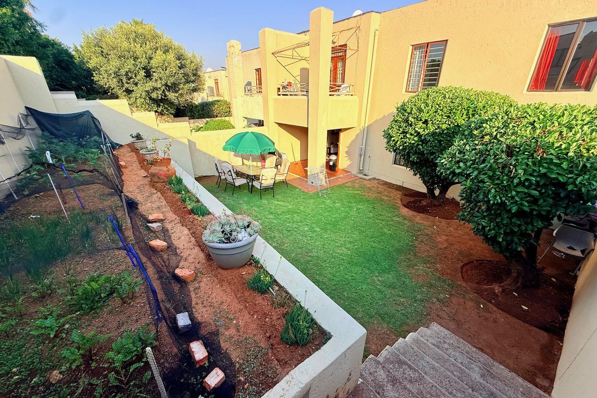 A rear view of the apartment featuring a private garden, a small lawn area, and a covered patio space.