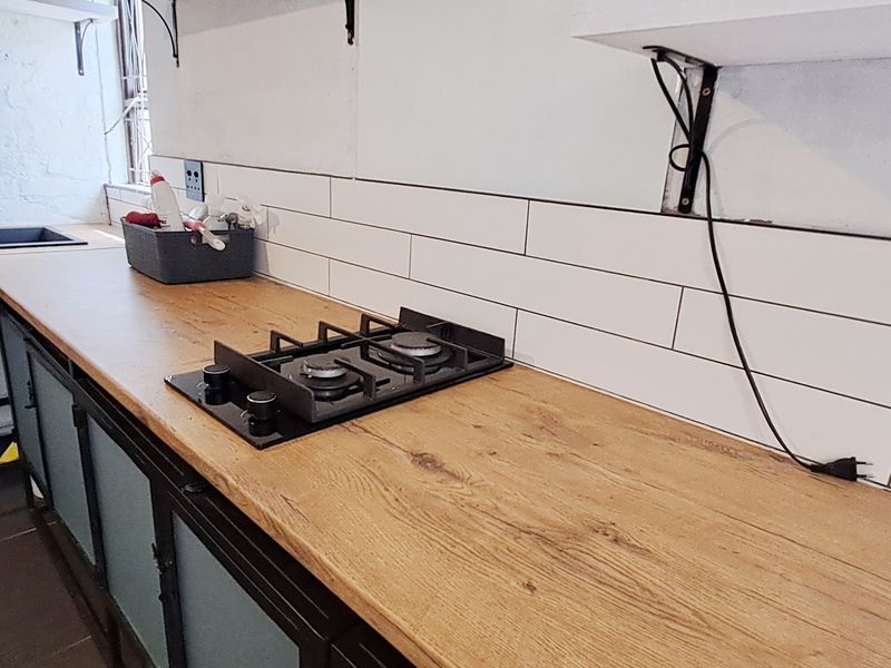 Kitchen area featuring a wooden countertop, built-in gas hob, subway tile backsplash, and an undermount sink with gooseneck faucet.