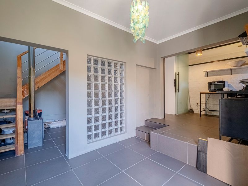 Open plan living area featuring tiled floors, a unique glass block feature wall, and a wooden staircase leading to an upper level.