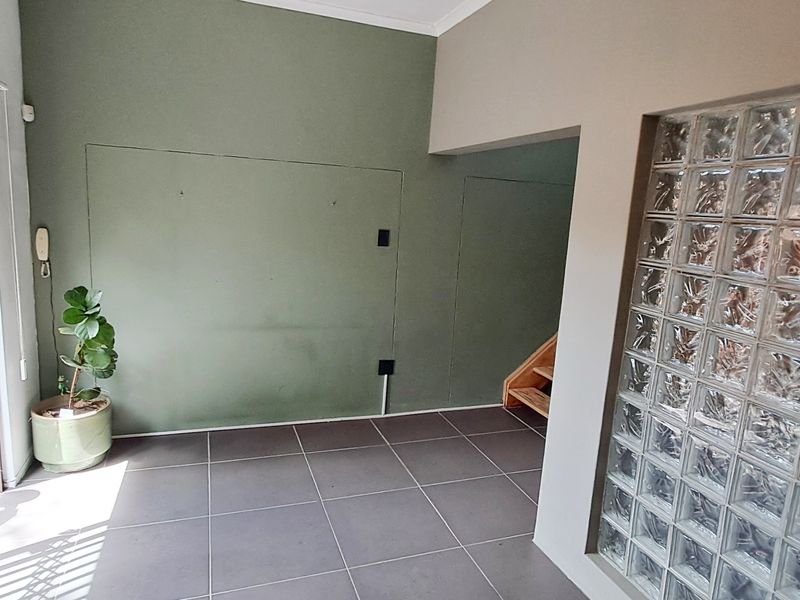 Entrance area featuring tiled flooring, a decorative glass block wall, and a security gate leading to the exterior.