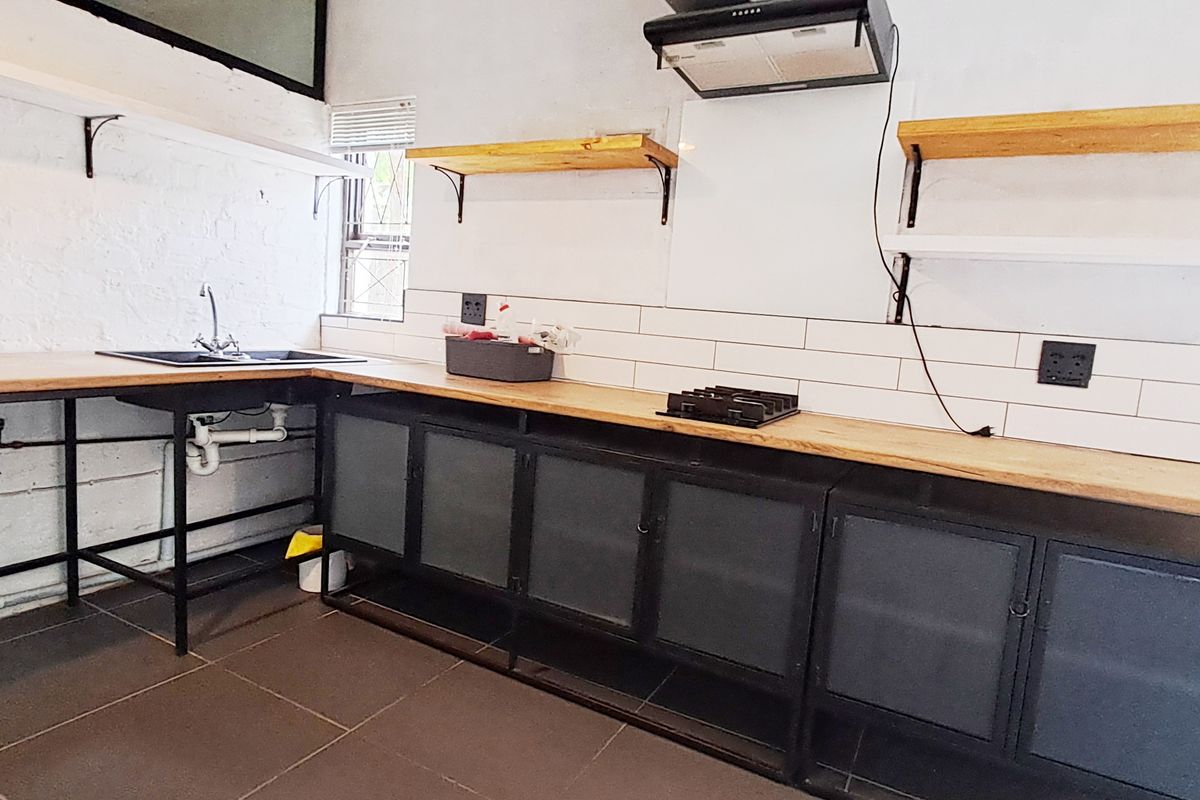 Industrial-style kitchen featuring metal cabinetry, wooden countertops, subway tile backsplash, and built-in hob with extractor fan.