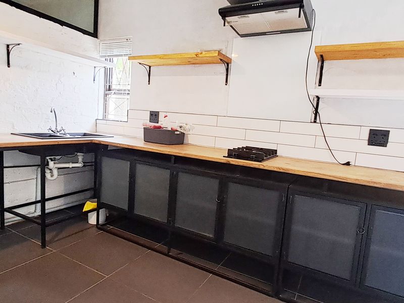 Industrial-style kitchen featuring metal cabinetry, wooden countertops, subway tile backsplash, and built-in hob with extractor fan.