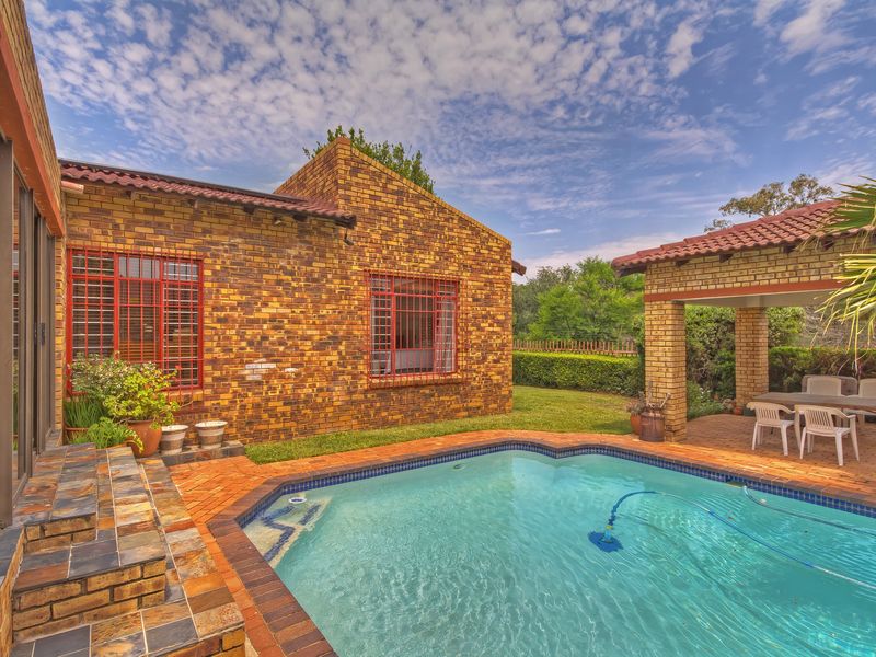 A well-maintained outdoor pool area featuring a swimming pool, brick-paved surround, and a covered patio space, ideal for outdoor relaxation and entertainment.