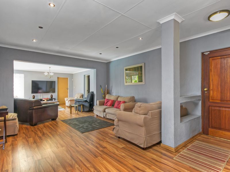 Spacious open-plan living area featuring warm laminate flooring, recessed lighting, and a distinctive built-in wall niche near the timber entrance door.