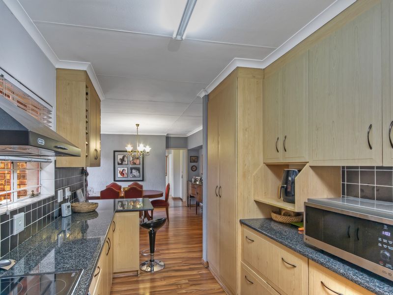 Functional kitchen featuring light wood cabinetry, dark granite countertops, tiled backsplash, and integrated extractor fan, flowing into the adjacent dining area.