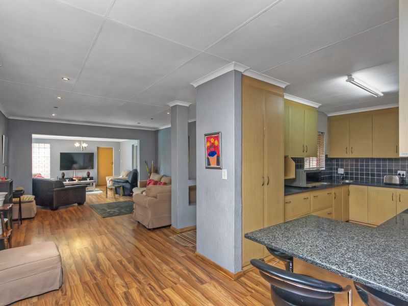 Open-plan living area featuring laminate flooring, recessed lighting, and a functional kitchen with granite countertops and ample built-in cabinetry.