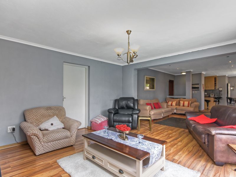 Open plan living area featuring laminate flooring, coved ceilings, and a connected kitchen space with breakfast bar seating.