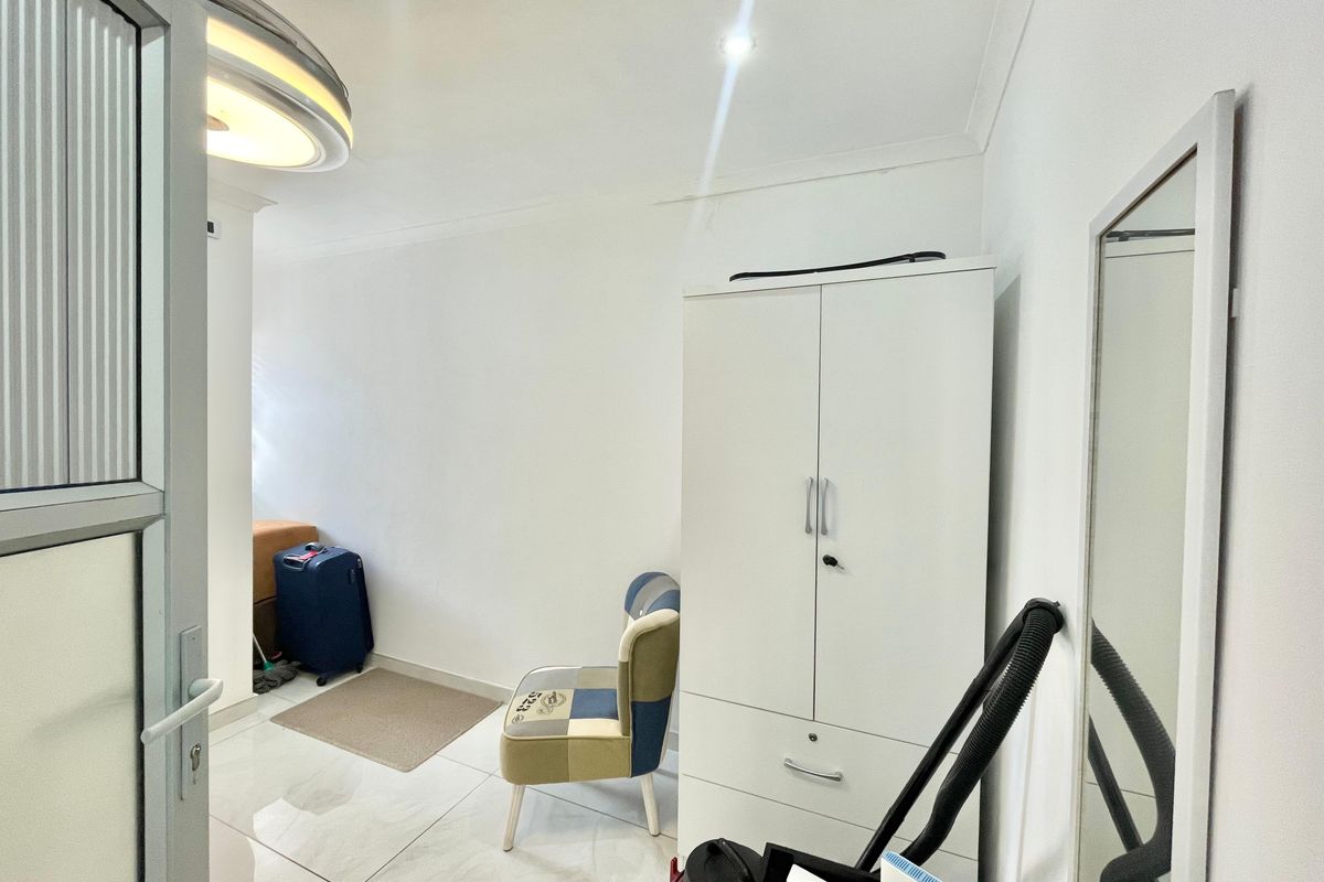 A bedroom featuring tiled flooring, a built-in wardrobe, and recessed ceiling lighting, offering a clean and functional space.
