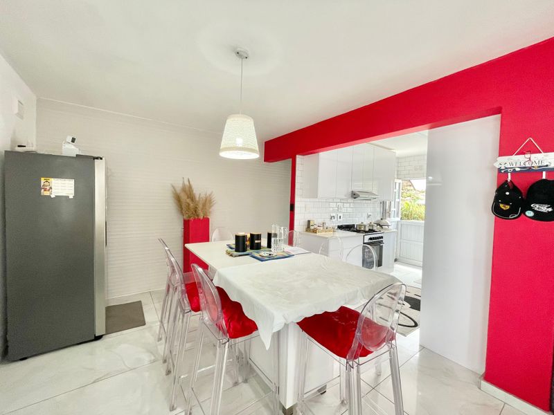 Open-plan kitchen and dining area featuring modern white cabinetry, subway tile backsplash, gas stove, and bright tiled flooring.
