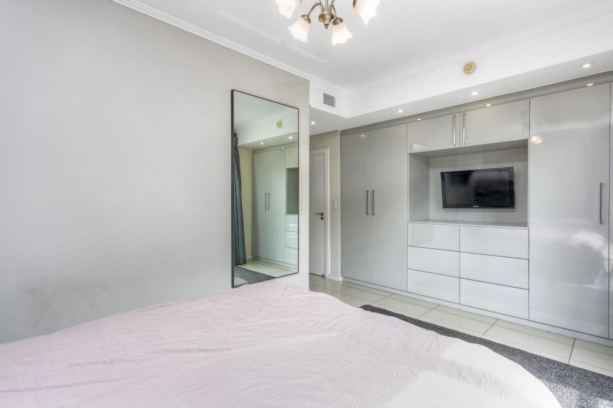 A well-maintained bedroom featuring extensive built-in cabinetry with integrated storage and a sleek, modern finish.