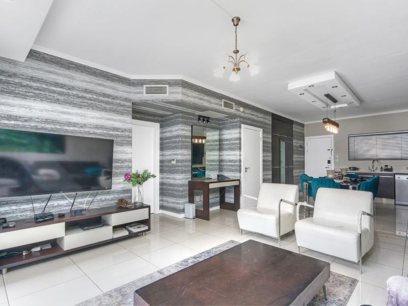 Open plan living and dining area featuring tiled flooring, modern recessed ceiling lighting, and decorative wall finishes.