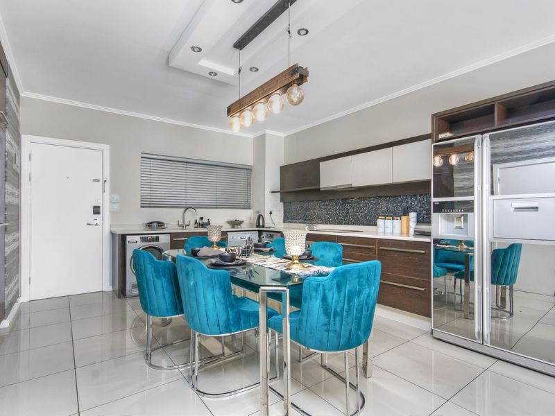 Modern open-plan kitchen featuring sleek cabinetry, integrated appliances, tiled flooring, and a contemporary drop-down ceiling feature with recessed lighting.