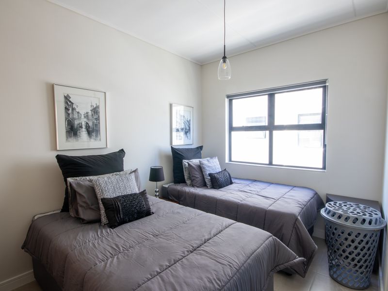A well-lit bedroom featuring neutral walls, tiled flooring, and a large window providing natural light.
