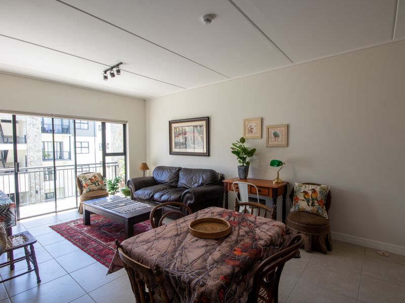 Open plan living and dining area featuring tiled flooring and large sliding glass doors leading to a balcony.