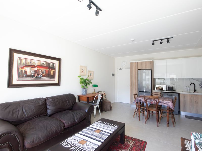 Open-plan living area featuring a modern kitchen with built-in cabinetry, laminate countertops, and tiled flooring throughout.