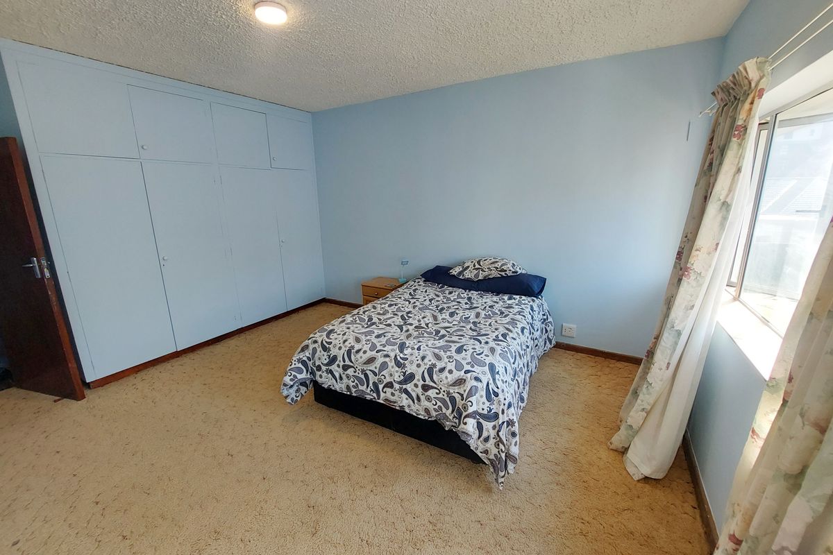 A spacious bedroom featuring built-in floor-to-ceiling cabinetry, neutral wall finishes, and carpeted flooring, offering ample storage and natural light.